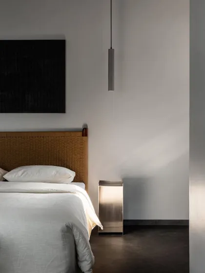 The sunlit master bedroom, highlighting the texture of the handwoven headboard. The play of light and shadow across the materials is a key part of creating a dynamic yet peaceful space.