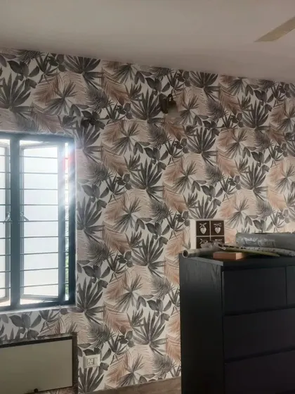 A bedroom with a multi-colored tropical leaf wallpaper. The pattern adds a vibrant and energetic feel, perfect for a modern home.