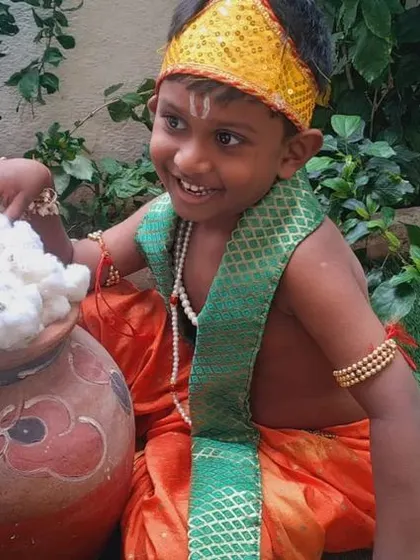 Our little Krishna enjoying his pot of 'butter' during the Janmashtami celebration. Role-playing is a fun way for children to engage with festival stories.