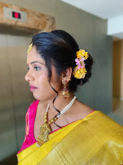 A side profile showing her elegant messy bun adorned with fresh yellow flowers, perfectly complementing her traditional attire.