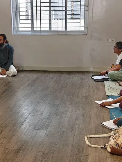 A theory session with Sudarshan Ji. Students take notes as they dive into the profound philosophy of yoga, connecting the physical practice to its spiritual roots.