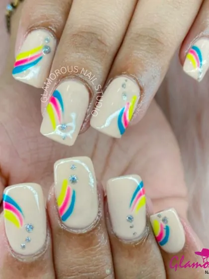 A playful design on a nude base, this look features a rainbow-like arc of blue, pink, and yellow, accented with tiny rhinestones.