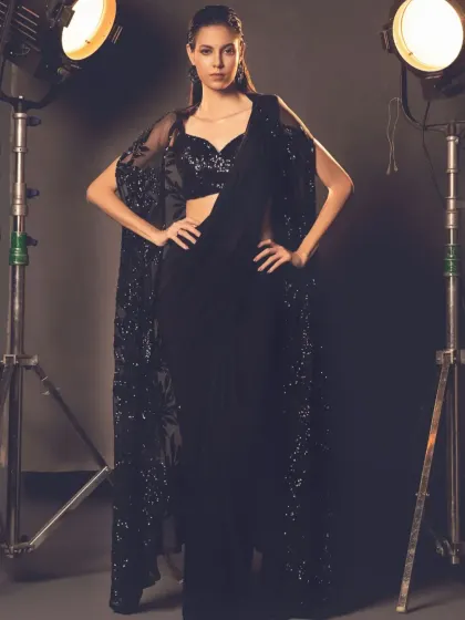 This all-black cape saree is the epitome of chic. The sheer, sequined cape adds a layer of drama and sophistication to the simple drape, creating a powerful and modern look.