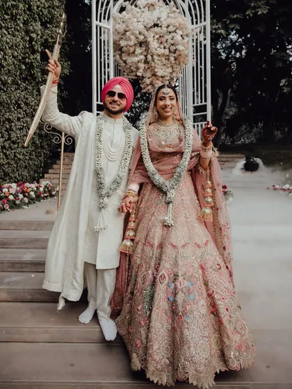 The newly married Sikh couple walks down the steps, hand in hand, surrounded by celebratory smoke, ready to begin their new life together.