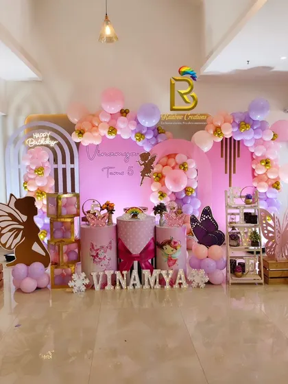A whimsical fairy and butterfly-themed party in shades of pink and lavender, featuring elegant arch backdrops and delicate butterfly wing cutouts.