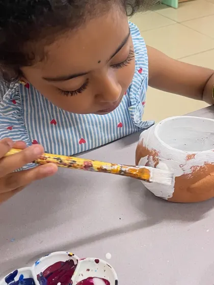The first step in planter painting is applying a solid base coat of white paint, as this little artist demonstrates.