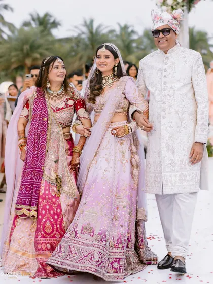 A proud father and mother walk their daughter down the aisle at her beach wedding in Goa, a moment filled with love and emotion.