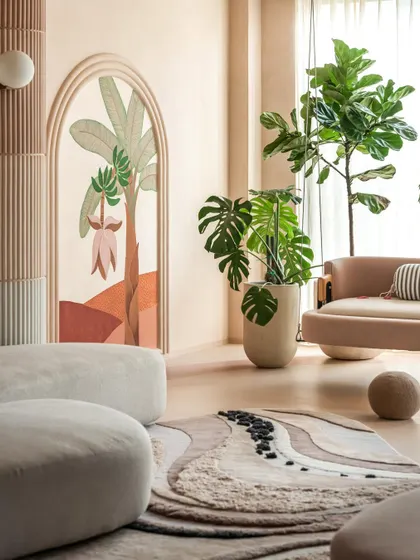 The hand-painted mural, framed by a soft arch, serves as a beautiful backdrop in this calm living space. We layered the home with lush greenery to honor the clients' love for nature, infusing every corner with life.