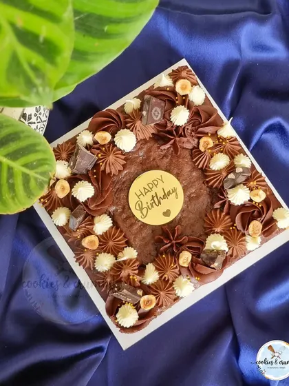 This square brownie cake is a statement in itself. It's decorated with rich chocolate and hazelnut piping, whole hazelnuts, and a "Happy Birthday" topper.