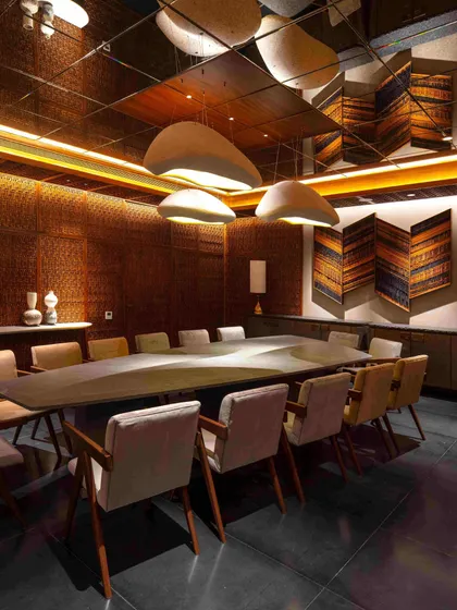 The dining room, located in the basement, is transformed into an intimate, jewel-box-like space with Pinjirakari-inspired lattice work. The room features artwork by Kumarasen Selveraj and a 'Window Series' by Shalini Dam.