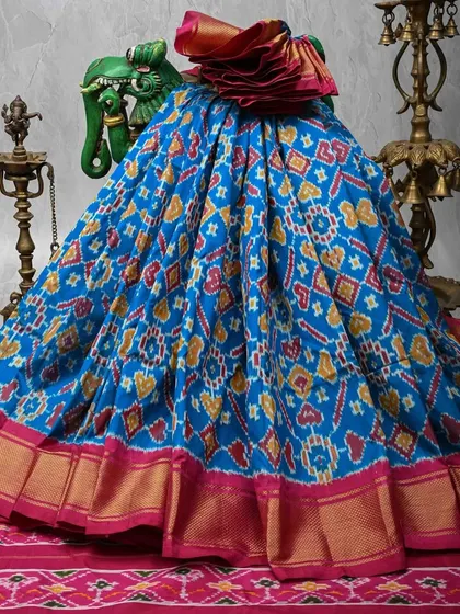 A vibrant blue Patola silk saree with traditional Ikkat patterns in red and yellow. The rich pink and gold border adds to its festive appeal. This is the same saree as 59.