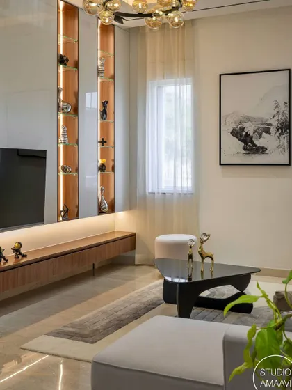 This living area is designed for entertainment and relaxation. A floating wooden console sits below the TV, flanked by vertical, back-lit display niches. The modern chandelier and abstract art complete this stylish and functional media wall.