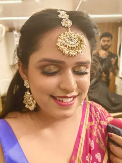 A close-up of our party makeup service. This client chose a golden glitter eyeshadow to match her jewelry, paired with a defined smokey liner and a warm pink lip, creating a festive and radiant look.