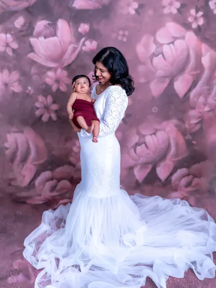 A mother's first portrait with her newborn. This elegant studio photo with a floral backdrop is a beautiful way to celebrate motherhood.