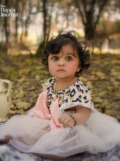 A baby's first picnic. This close-up portrait of a baby girl sitting on a blanket in the woods is full of innocent charm.