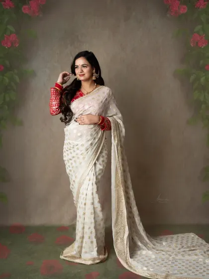 The elegance of a white saree. This mom-to-be looks serene and graceful in a beautiful white and gold saree, complemented by a red embroidered blouse.