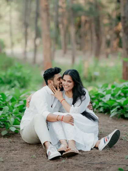 A playful and intimate moment in the woods, with the groom-to-be whispering in his partner's ear as she laughs. This candid shot is full of personality and love.