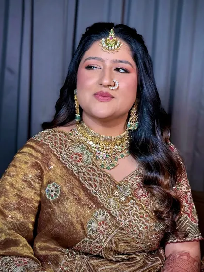 A close-up portrait showing the bride's glowing skin, soft pink eyeshadow, and elegant jewelry.