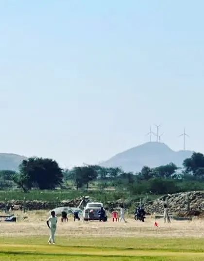 A scenic view of a match in progress during our tour of Chitradurga in 2023, with windmills in the background.