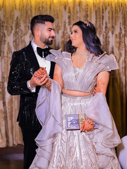 A sweet moment between the couple, holding hands and sharing a look. The bride's stylish reception outfit and quirky clutch are highlighted in this shot.