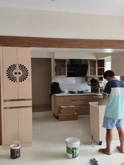 A work-in-progress shot of an open-plan kitchen and dining area. You can see our craftsman at work, ensuring every detail, like the intricate design on the pantry unit, is executed perfectly.