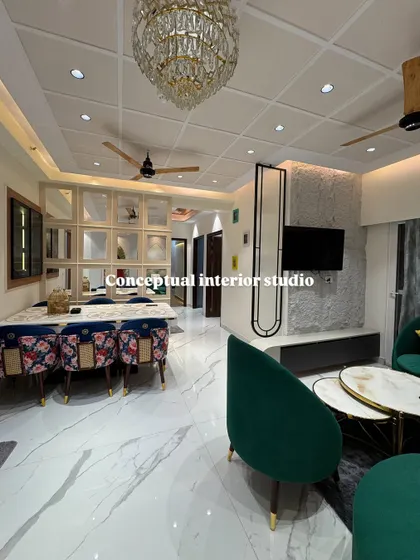 An overview of the open-plan living and dining area in a 4BHK. The crystal chandelier and cohesive design elements tie the entire luxurious space together.