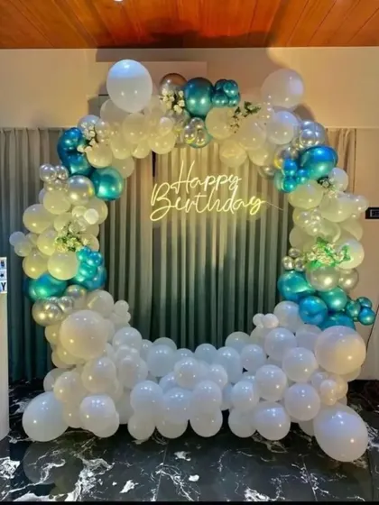 An elegant and airy balloon ring in white and metallic teal. This minimalist design is perfect for a modern celebration, with a neon "Happy Birthday" sign providing a central focus.