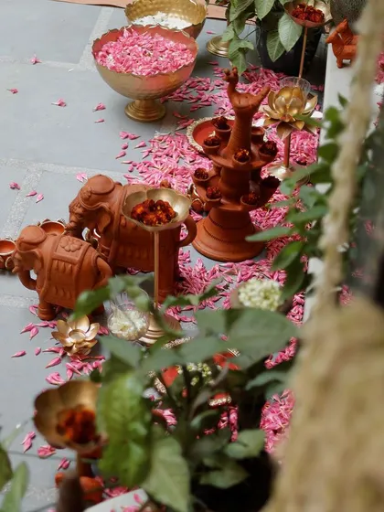 A glimpse of the decor through foliage, showing terracotta elephants and lamps. This perspective creates a sense of discovery and highlights the layered design.