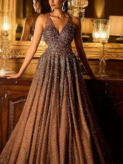 A stunning bronze-colored gown with a cut-out detail at the waist. The all-over sequin work makes it an incredibly glamorous choice for an evening event.