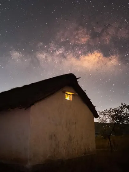 The galactic core shines above a small hut in the Kalpavalli Community Conservation Area. This image highlights the impact of light pollution from urban areas, which creates a glow that obscures the stars.