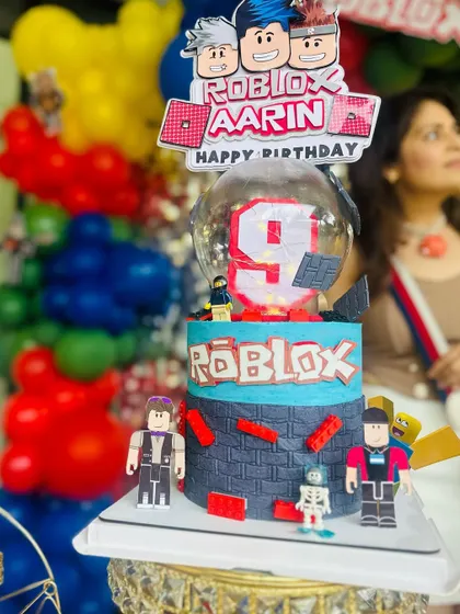 The cake is the star of the show, and I make sure it fits the theme perfectly. Here is a detailed Roblox-themed cake, complete with character figures, placed on one of my decorative stands.