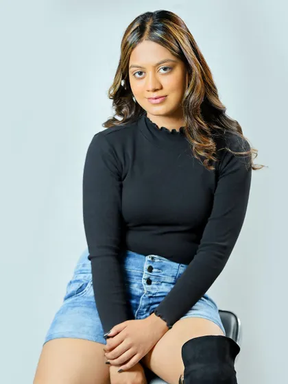 A seated portrait with a more edgy look, featuring a black top and thigh-high boots to show versatility.