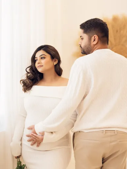 A gentle touch full of meaning. The father-to-be reaches out to gently touch his partner's belly, a simple yet powerful gesture of connection with their unborn child.
