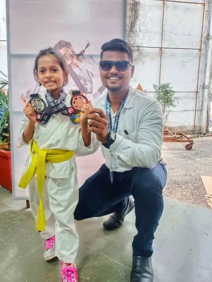 A young yellow belt student proudly shows off her two medals from the national karate championship in Mumbai.