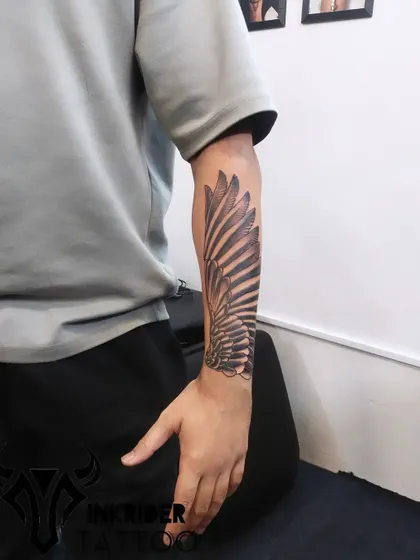 This large wing tattoo covers the length of the forearm. The detailed shading and strong vertical lines are very effective at drawing the eye away from and covering any old ink underneath.