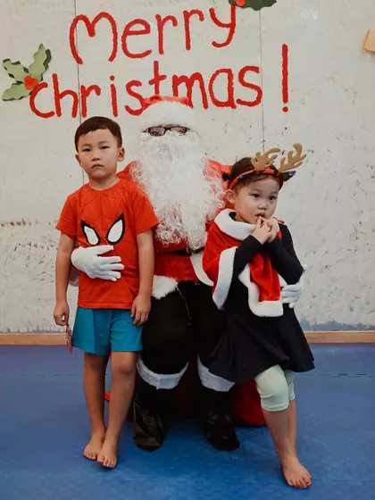 Two children, one in a Spiderman costume, pose with Santa.