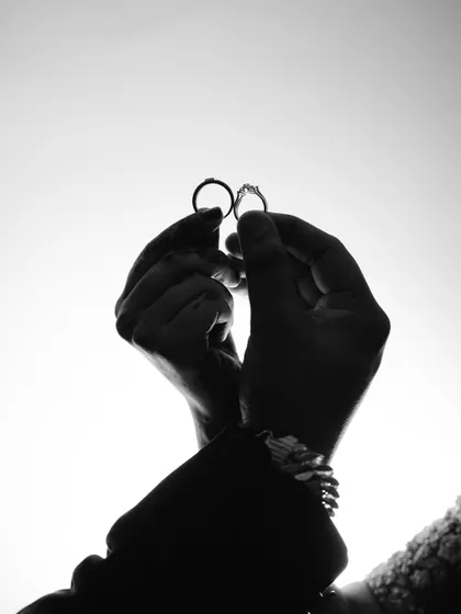A creative silhouette shot of the couple's hands holding their wedding rings up to the sky. This artistic photo is a beautiful way to symbolize their union.