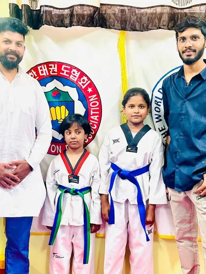 Siblings proudly showing their new belts with their coaches.