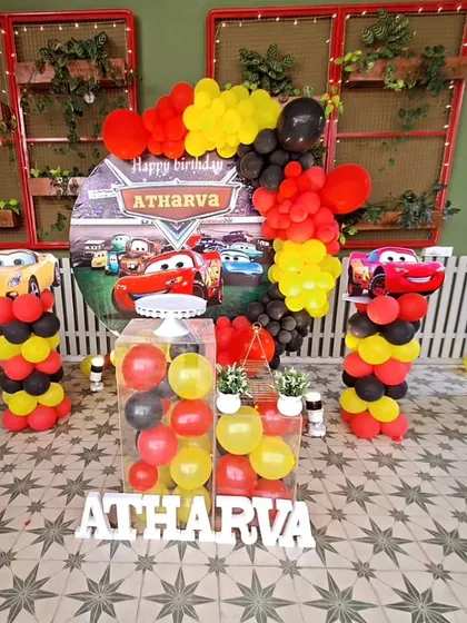 We designed this coustamised car theme for Atharva's second birthday. It includes a backdrop with all the famous characters, balloon columns, and transparent boxes filled with balloons for a unique touch.