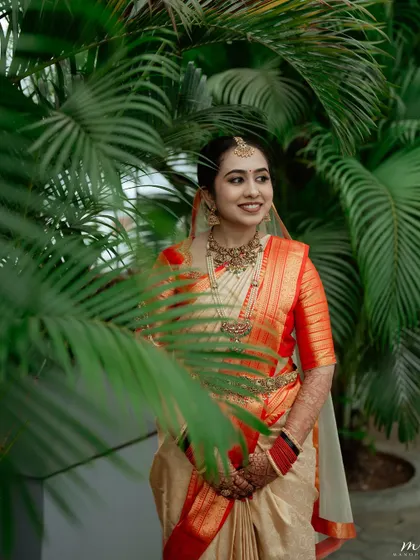 The bride framed by lush greenery. Her natural-looking makeup and traditional attire create a timeless and serene bridal portrait.