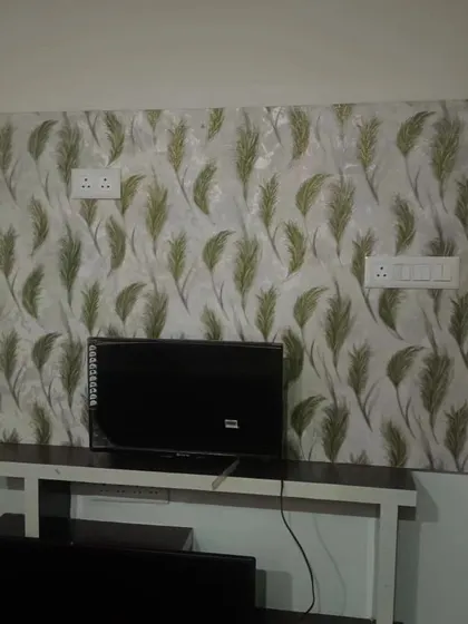 A feather-patterned wallpaper used as an accent behind a TV console. The design adds a soft, natural touch to the living area.