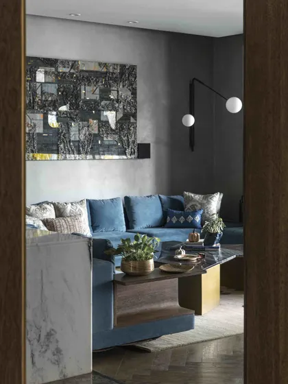 A glimpse into the family lounge from the doorway, highlighting the deep, moody color palette and the sophisticated layering of art, lighting, and custom furniture.
