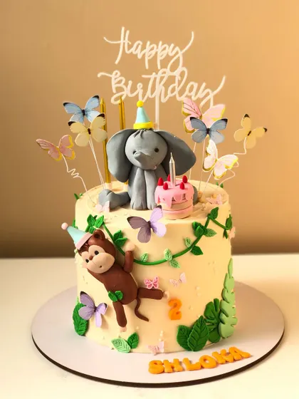 A sweet jungle-themed cake with a playful monkey and a cute elephant celebrating a birthday.