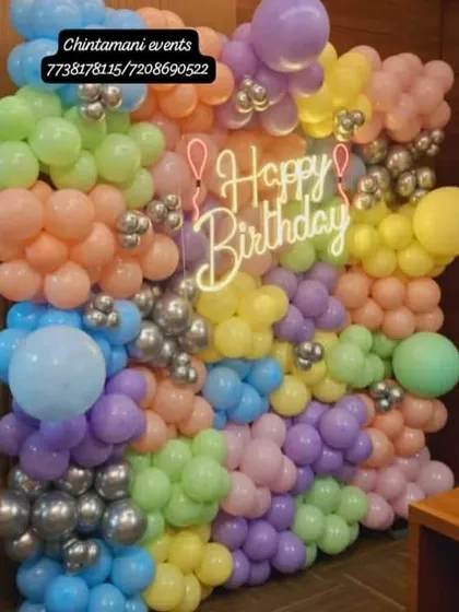 Pastel and metallic balloons cover our birthday wall, with a glowing birthday sign at the centre of the arrangement.