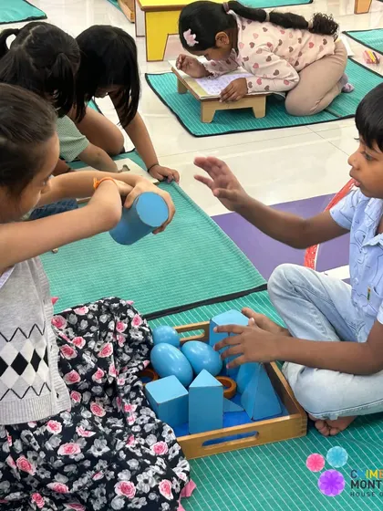 Two children work together with geometric solids, the older child explaining the shapes to the younger one in a beautiful display of peer teaching.