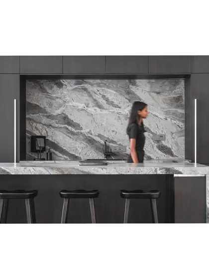 A wider view of the kitchen and bar, showcasing the dark wood cabinetry that provides a beautiful contrast to the veined stone.