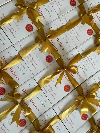 A large quantity of the book "Don't Believe Everything You Think," each individually wrapped with a golden ribbon. This is an example of a thoughtful and uniform gift for corporate seminars or employee wellness programs.