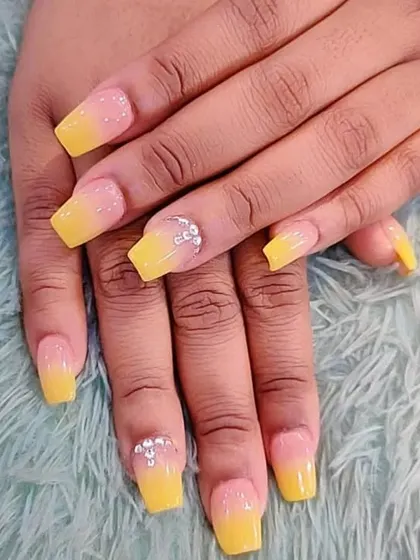 Another example of the ombre technique, this time with a soft yellow gradient on square-shaped nails. The design is elevated with a delicate crystal placement on the accent nail.