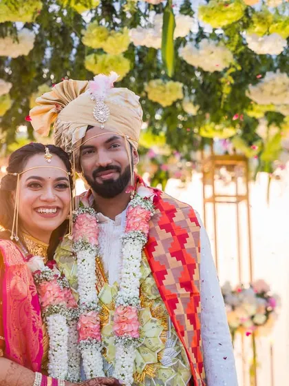 Kavya and Suraj, beaming with happiness under a canopy of flowers after their wedding ceremony.