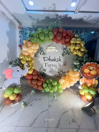 A circular balloon arch with jungle leaves and cute animal cutouts creates a perfect photo spot for this 3rd birthday party.